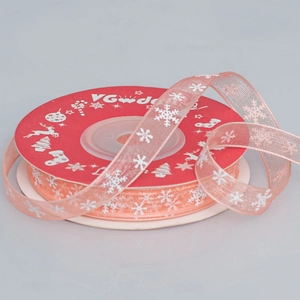 Detail of 1cm pink sheer Christmas snowflake organza ribbon on festive red spool