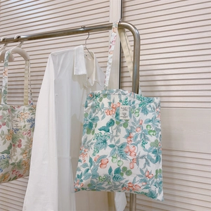 Detailed berry print canvas tote bag with woven label hanging on a rack