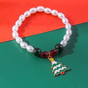 Detail of Christmas beaded bracelet with green tree charm and red faceted beads