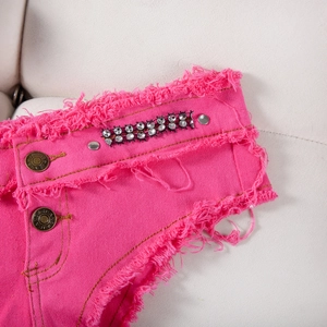 Dettaglio degli shorts in denim rosa con strass scintillanti e bordi sfilacciati