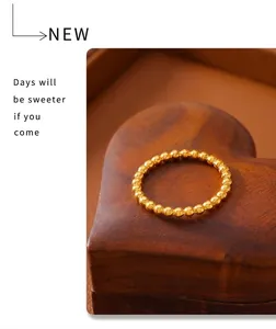 Detailed view of a polished gold beaded ring placed on a textured heart-shaped wooden surface