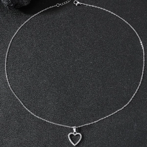 Minimalist silver heart pendant necklace with shimmering crystals on a black stone background