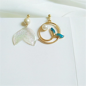 Detail of asymmetric whale tail earrings with blue enamel and white pearls