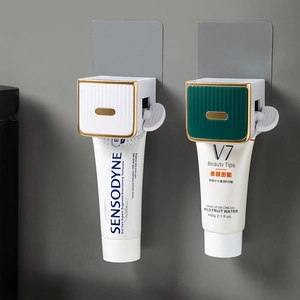 Wall-mounted toothpaste squeezer in white and dark green with elegant gold trim details