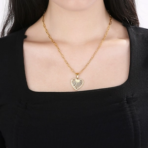 Close-up of gold heart necklace with cutout fan design and micro-pave crystals on model