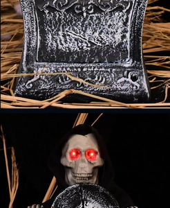 Close-up of Halloween gravestone with glowing red eyes skull and embossed texture detail