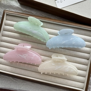 Detail of four large marble pattern hair claws in mint, blue, pink, and cream colors