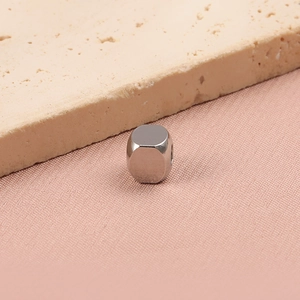 Detailed view of square silver stainless steel spacer beads on a textured surface