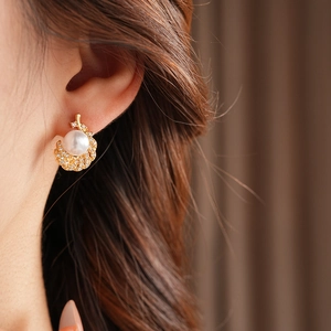 Detail of golden feather pearl earrings with zircons shown on a model's ear
