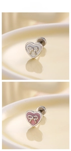 Macro display of pink and white heart earrings with bowknot details on ceramic tray