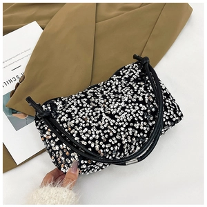 Close-up of sparkling silver sequins on black leather shoulder bag with sleek handle