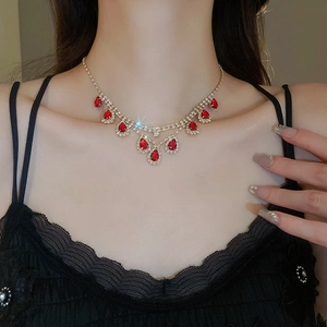 Close-up of gold choker with red teardrop gemstone and tassel necklace on a model