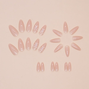 Glossy nude pink almond press-on nails with white bow designs and tiny rhinestones