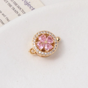 Macro detail of a gold rotating flower clasp with pink zircon heart petals and pavé crystals