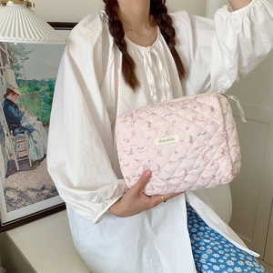 Trousse de toilette matelassée rose avec motifs ours, tenue par une femme en lumière douce