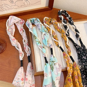 Floral print headbands with pearls and rhinestones in various colors on a wooden tray