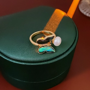 Detailed shot of golden butterfly ring with pearl on green silk jewelry box