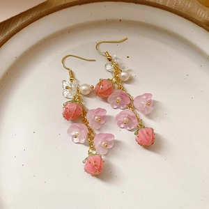 Macro detail of vintage floral tassel earrings with pink strawberry and flower beads