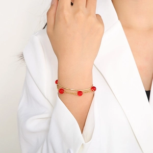 Close-up of double-layer gold stainless steel bracelet with red round beads on wrist