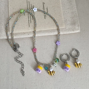 Beaded flower necklace and bee earrings set with honey jar charms on soft fabric