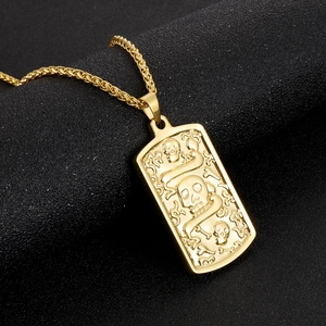 Macro shot of gold stainless steel necklace with gothic skull pendant on dark background
