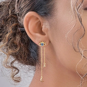 Close-up of gold chain earrings with blue evil eye, star and crescent moon pendants