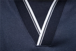 Detail of navy blue cotton polo shirt featuring V-neckline with white stripe ribbing