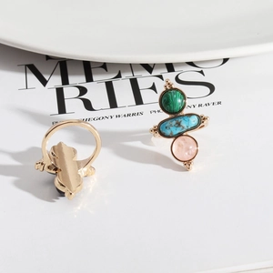 Bohemian gold ring set with green, blue, and pink natural stones on elegant ceramic plate