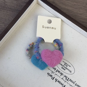 Détail d'élastiques à cheveux en feutre de laine avec cœurs en peluche et logo Suanmu