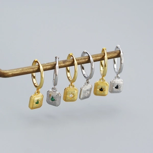 Detailed view of gold and silver starburst earrings with green, white, and black gems