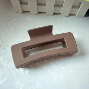 Matte brown rectangular claw clip for thick hair shown on a white textured background