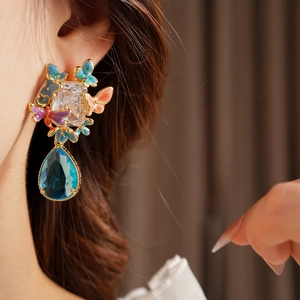 Detailed view of colorful enamel butterfly earrings with a blue crystal water drop