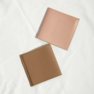 Flat lay of brown and pink PU leather storage pouches on white fabric background