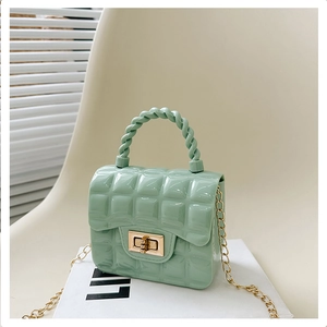 Close-up of mint green jelly bag featuring quilted PVC texture and gold chain strap