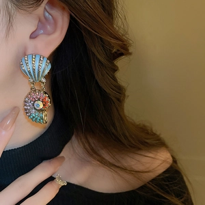 Close-up of vintage shell earring with blue enamel and colorful rhinestones on model