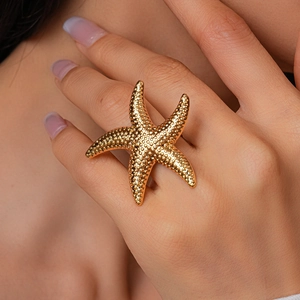 Detailed close-up of a large gold starfish ring featuring a textured metallic finish