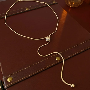 Close-up of gold-plated snake chain necklace with a sparkling cubic zirconia slider bead