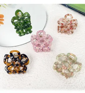 Detailed flat lay of five floral claw clips with rhinestone accents and marble textures