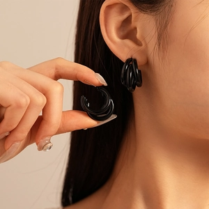 Détail de boucles d'oreilles multicouches noires en forme de C sur modèle au style chic