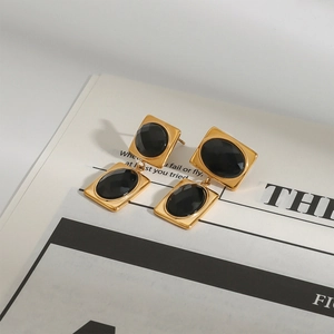 Detail of luxury gold and black gemstone stainless steel earrings on a magazine page