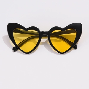 Close-up of heart-shaped sunglasses featuring black plastic frames and yellow tinted lenses