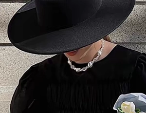 Baroque irregular necklace styled with a wide-brimmed black hat and pleated top