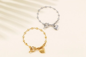 Close-up of gold and silver heart-shaped chain bracelets with toggle OT clasp detail