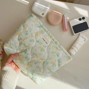 Detailed shot of floral quilted cotton makeup bag held by hand with beauty accessories