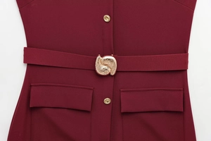 Detail of burgundy dress featuring golden spiral buckle belt and classic flap pockets