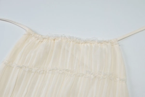 Dettaglio del top a pieghe crema con pizzo delicato e trama fine in chiffon