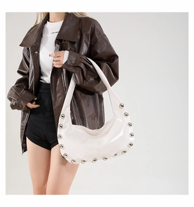 Detail of white crescent shoulder bag with silver studs and glossy leather texture