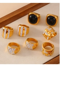Close-up of gold-plated titanium rings with black agate and pavé diamonds on a beige tray