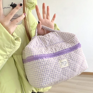 Detailed view of purple checkered quilted makeup bag with handle and zipper closure