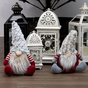 Two Christmas faceless gnome plush dolls with gray hats on a light wooden background